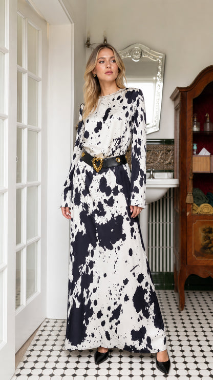 Front view of woman wearing white cow print long sleeve maxi dress with belt
