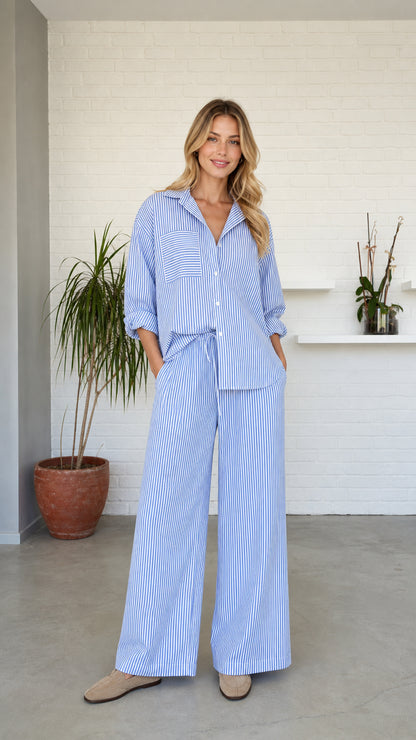 Woman standing wearing blue striped button-down shirt and wide-leg lounge pants