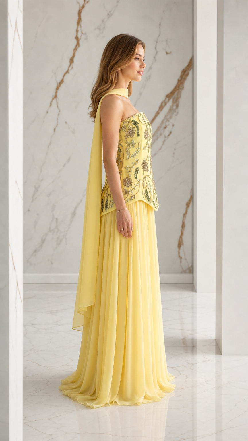 Side profile of yellow pleated maxi evening dress with embroidered bodice