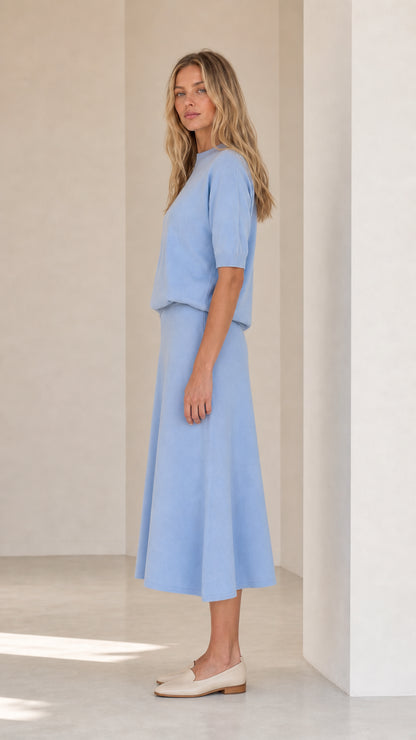 Side profile view of woman in light blue knit two-piece set with loafers