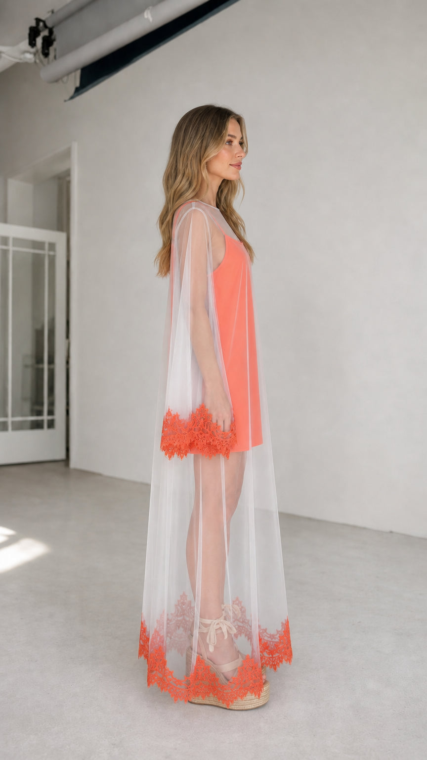 Model wearing coral two-piece set, side view showing longline mesh duster