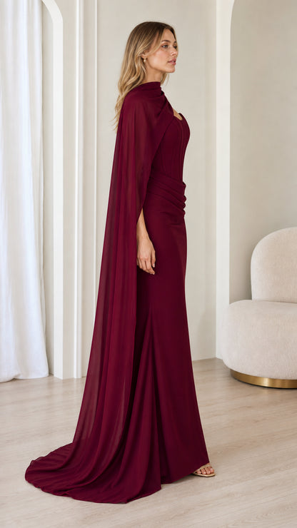 Side view of burgundy formal maxi gown with attached scarf cape