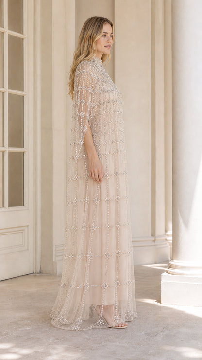 Side profile view of champagne beaded cape maxi gown