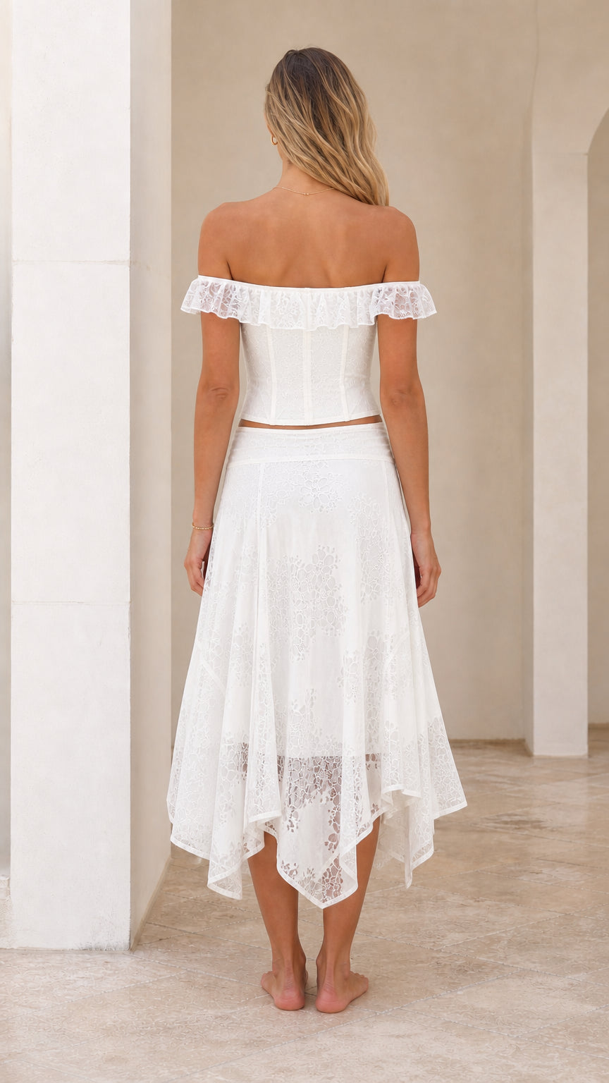 Back view of woman in white off-shoulder lace corset and midi skirt set