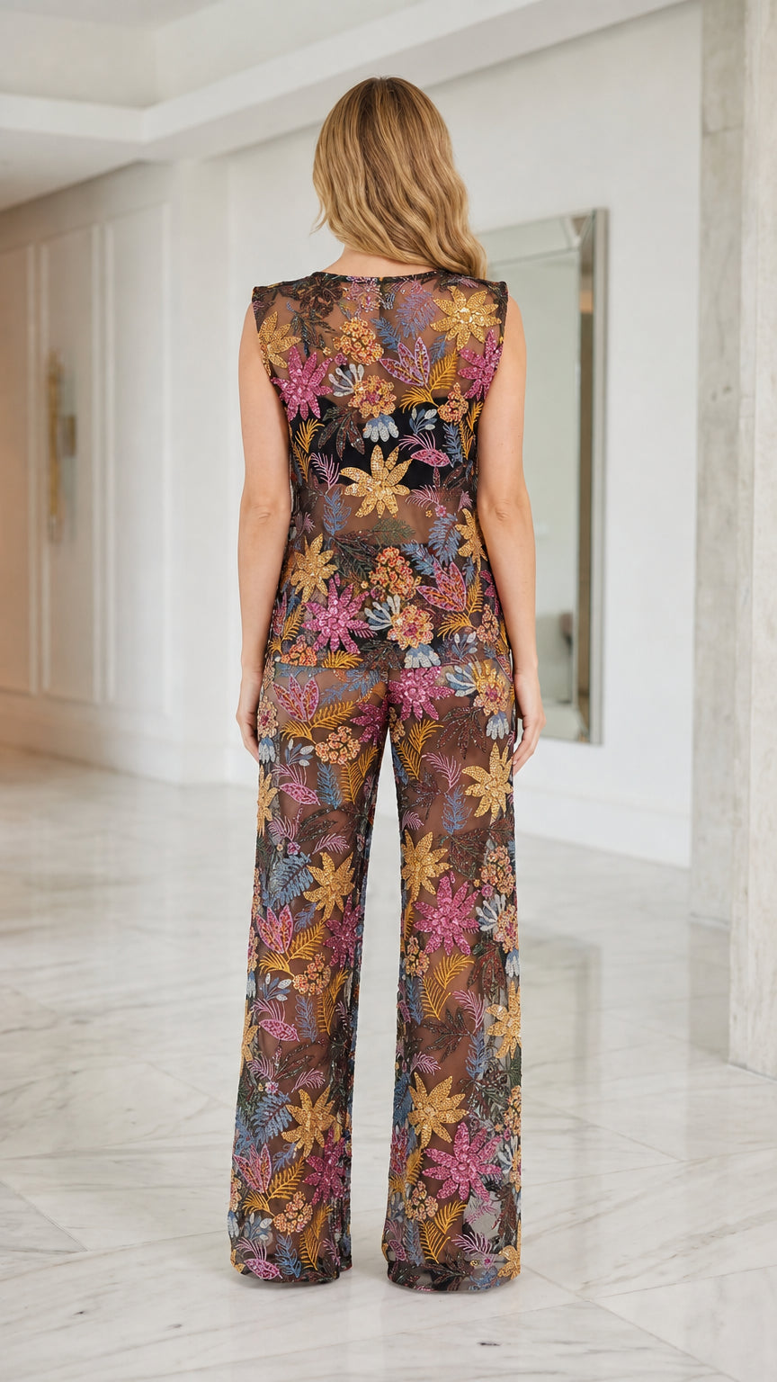 Back view of model in black sequin floral mesh two-piece set