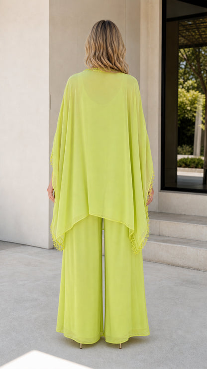 Back view of model wearing lime green flowing cape pants set
