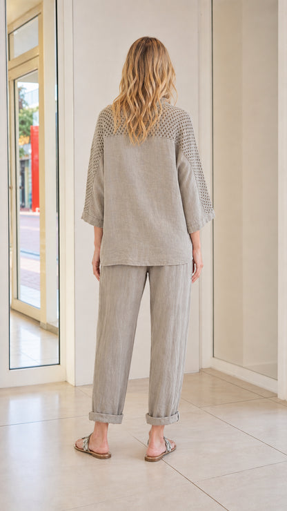 Back view of model showing crochet mesh sleeve detail on taupe top