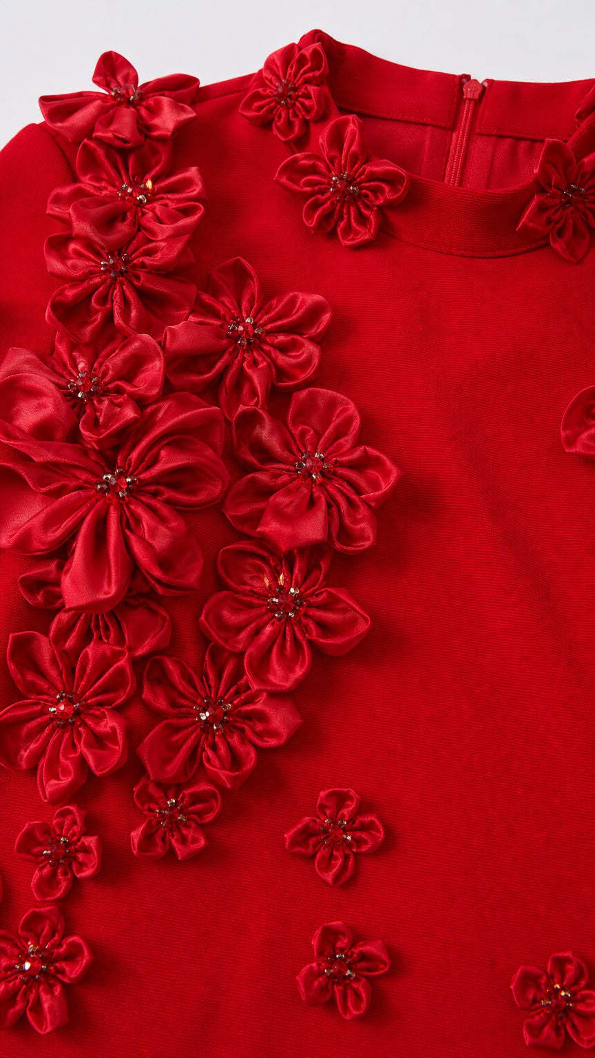 Close-up detail of red fabric flowers and beading on the gown