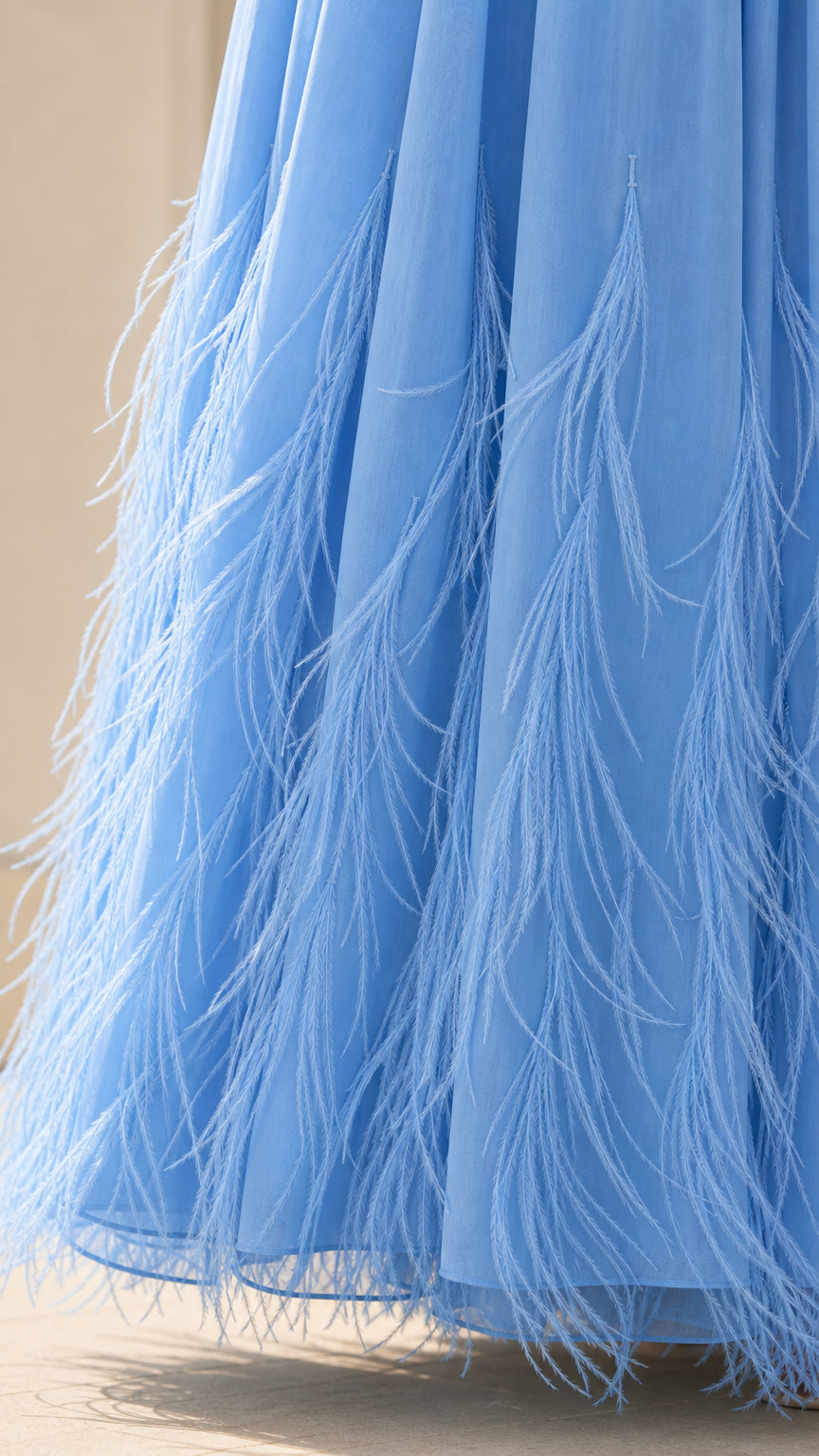 Close up of feather trim detail on the hem of the blue dress