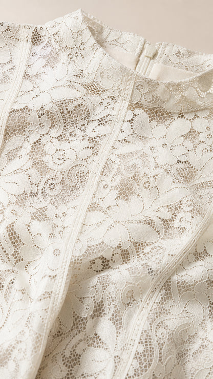 Close-up detail of white floral lace fabric and mock neckline