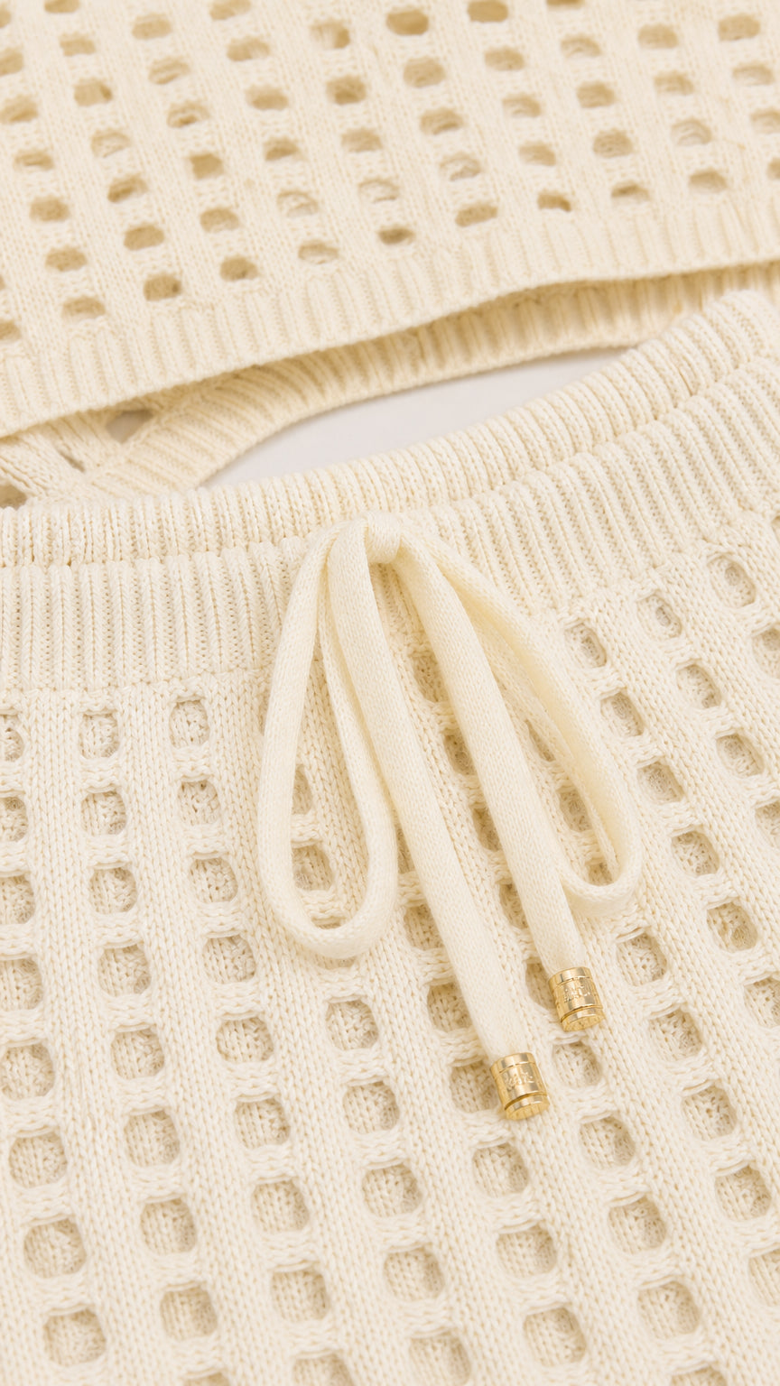 Close-up detail of off-white knit texture and drawstring waist
