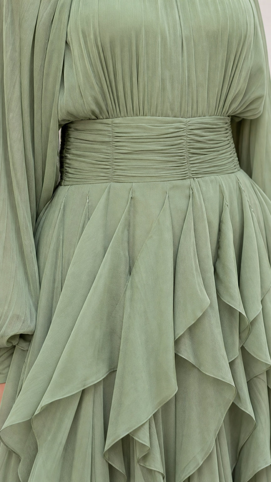 Close-up detail of ruched waistband and layered ruffles on sage green dress