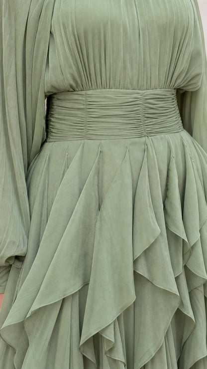 Close-up detail of ruched waistband and layered ruffles on sage green dress