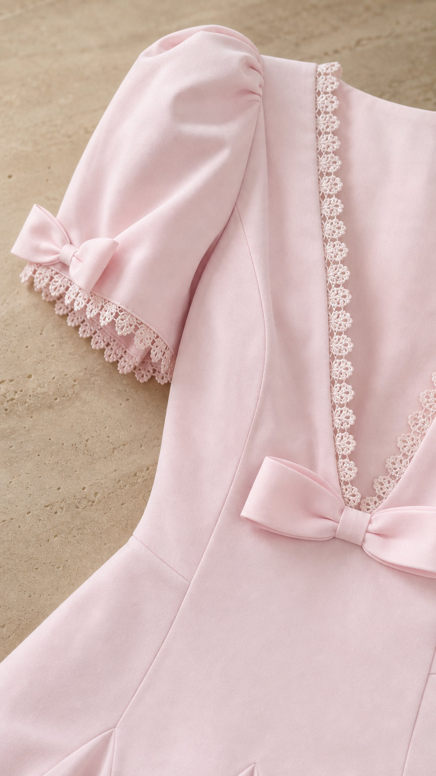 Close-up detail of puff sleeve, lace trim, and bow on pink dress