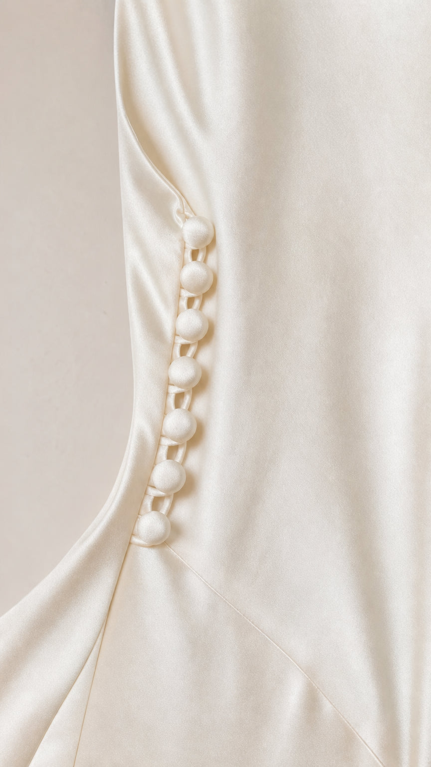 Close-up of decorative side buttons on ivory satin dress