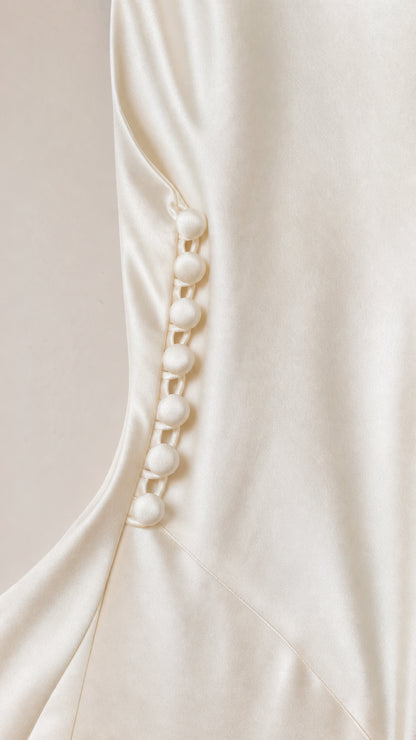 Close-up of decorative side buttons on ivory satin dress