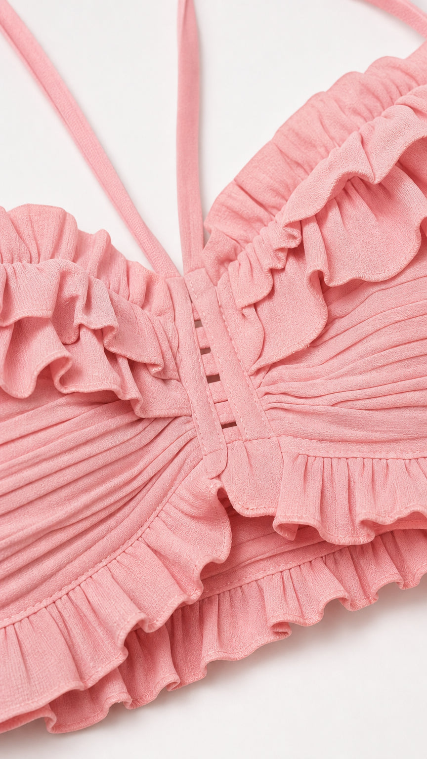 Close-up detail of textured ruffle and button accents on pink top