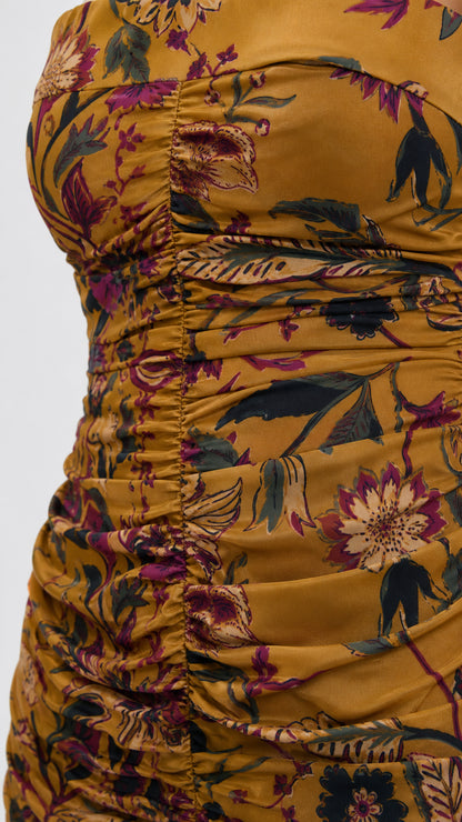 Close-up detail of fabric, print, and ruching on mustard dress