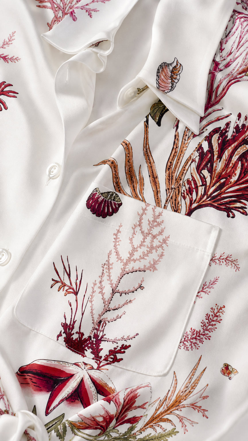 Close-up detail of smooth satin fabric, chest pocket, and coral print pattern