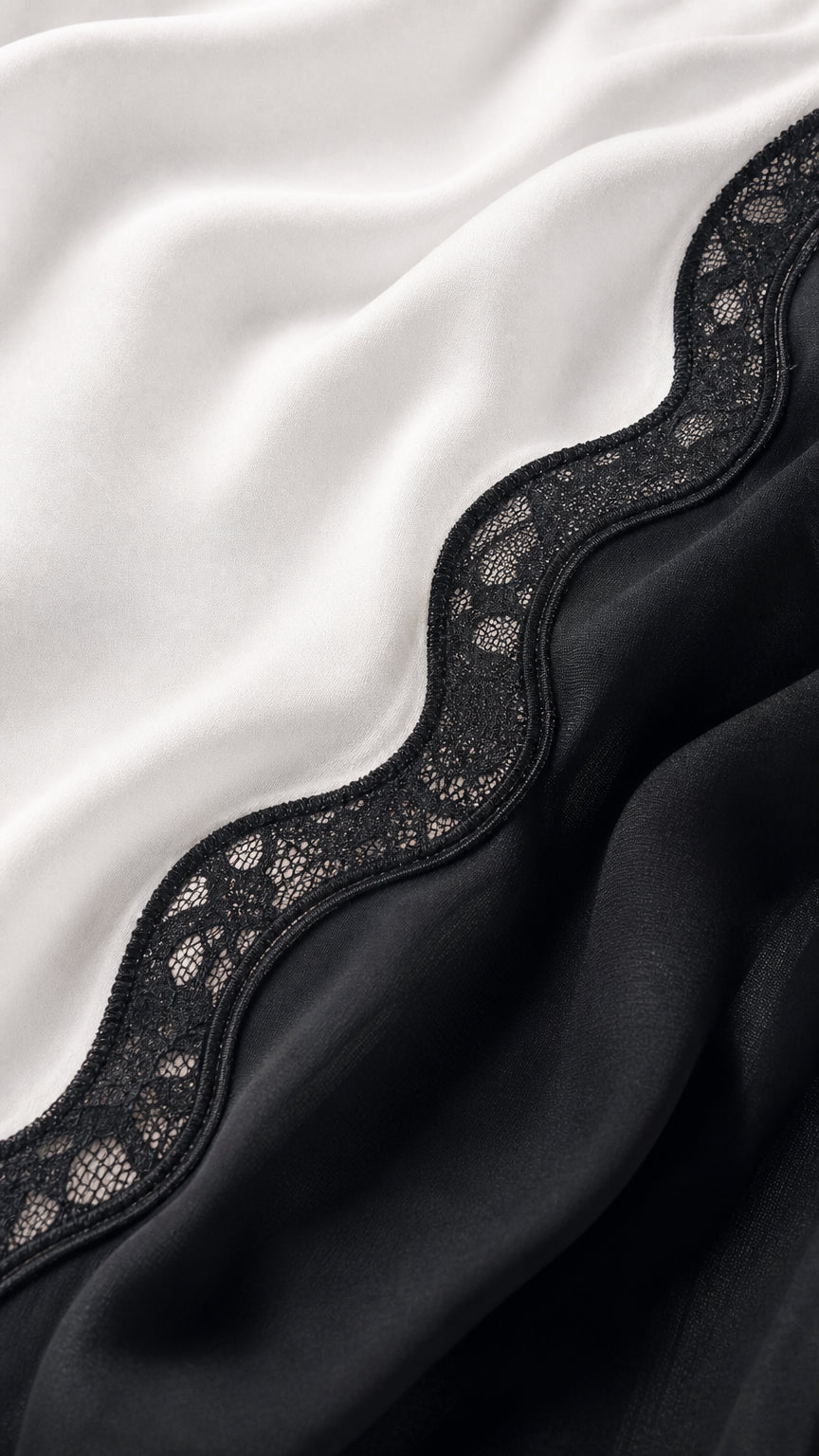 Close-up fabric detail showing white satin texture and black lace trim