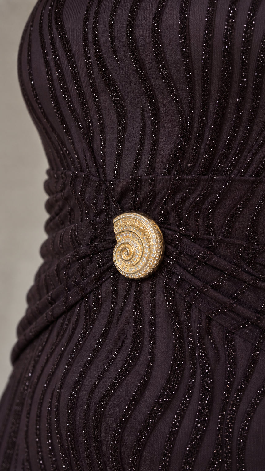 Close-up detail of the gold-tone spiral brooch and wavy glitter texture