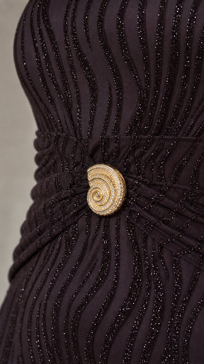 Close-up detail of the gold-tone spiral brooch and wavy glitter texture