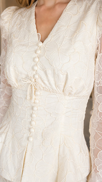 Close-up detail of the V-neckline, front buttons, and textured lace fabric