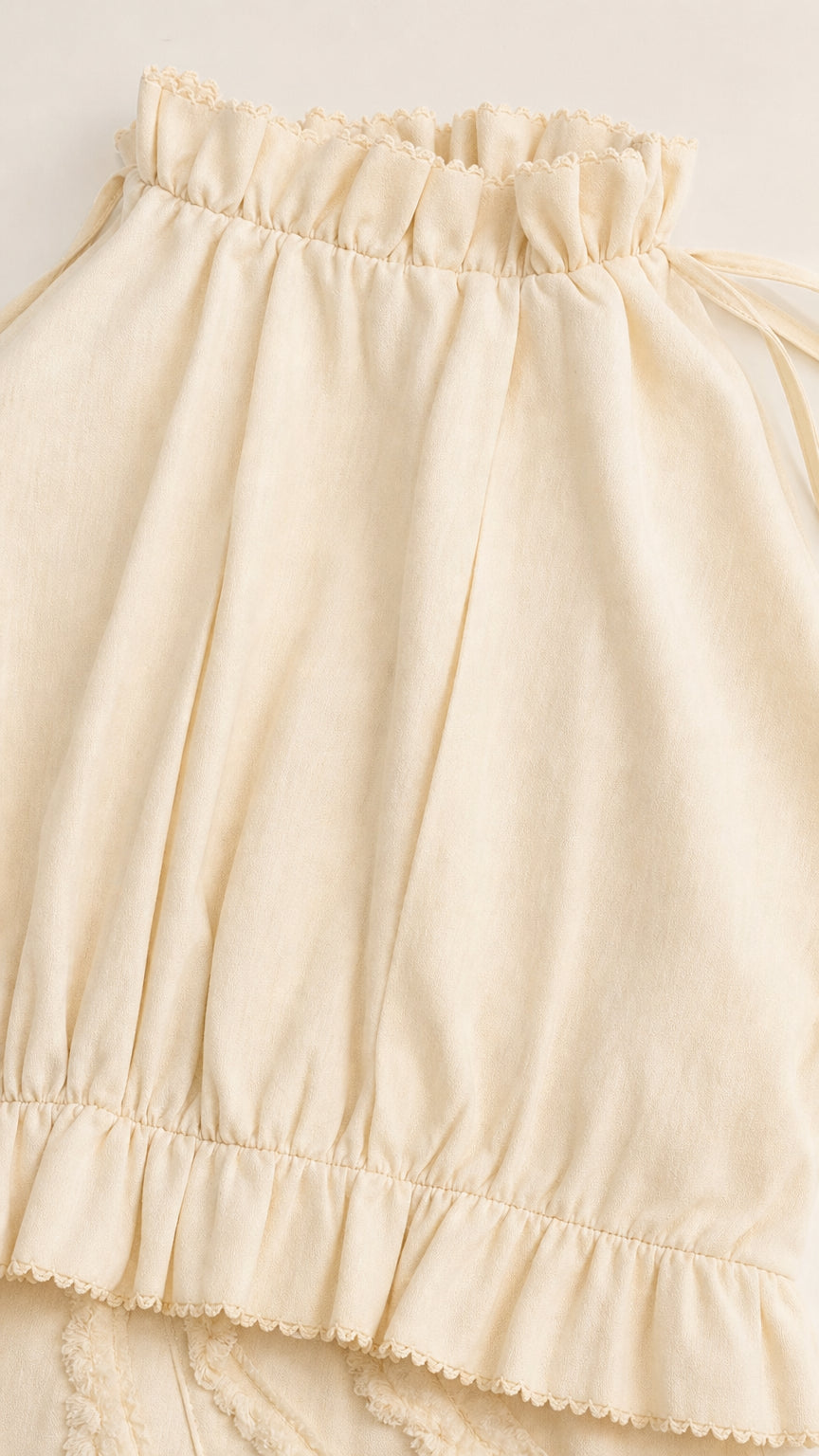 Close-up of ruffled halter neckline and fabric texture in Cream
