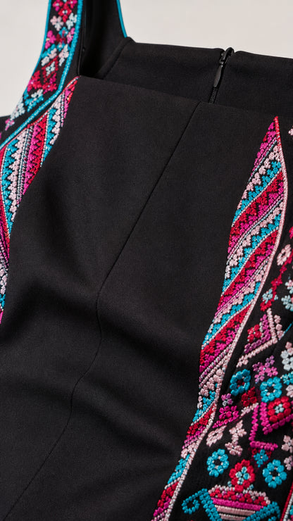 Close-up detail of side embroidery and square neckline on black dress