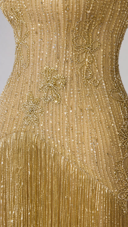 Close-up detail of intricate beadwork and sequin floral motifs on the gold dress