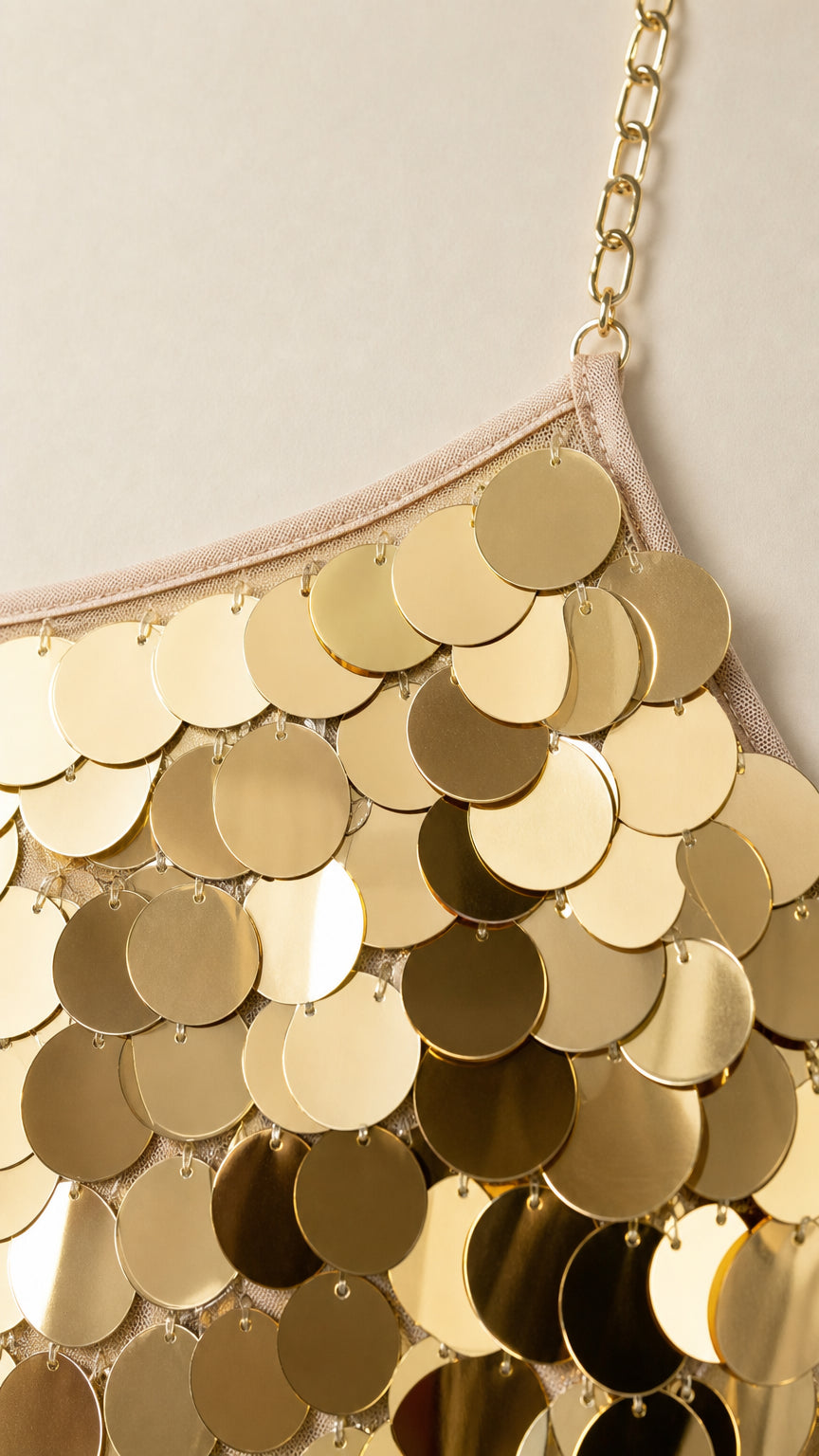 Close-up detail of oversized gold circular sequins and chain strap