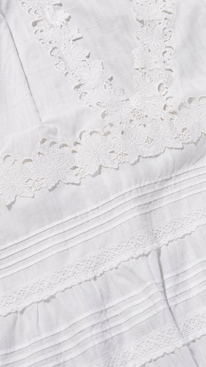 Close-up detail of white eyelet lace neckline and pintuck fabric