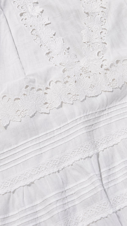 Close-up detail of white eyelet lace neckline and pintuck fabric