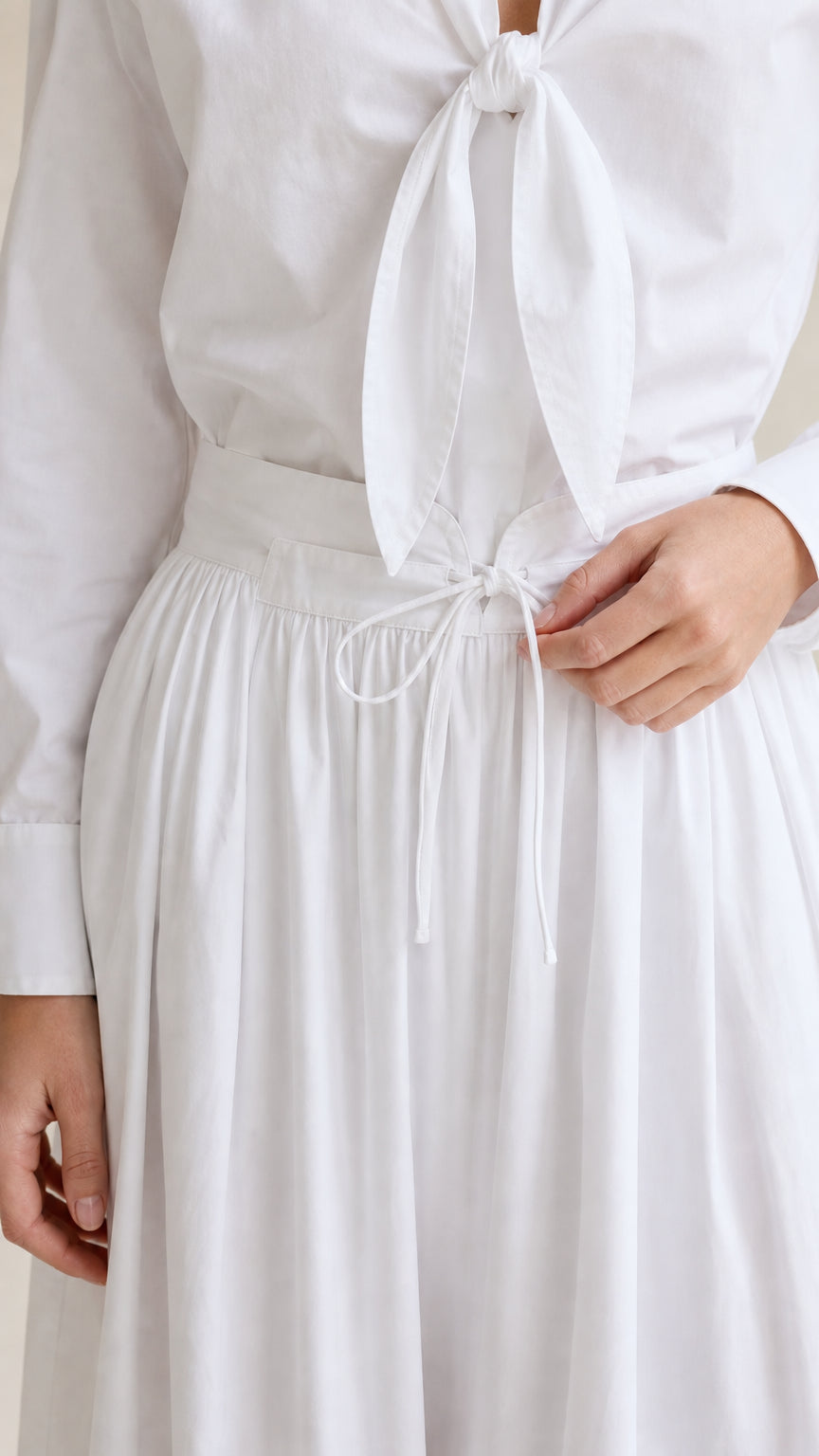 Close-up of white tie-front shirt knot and drawstring pants waist