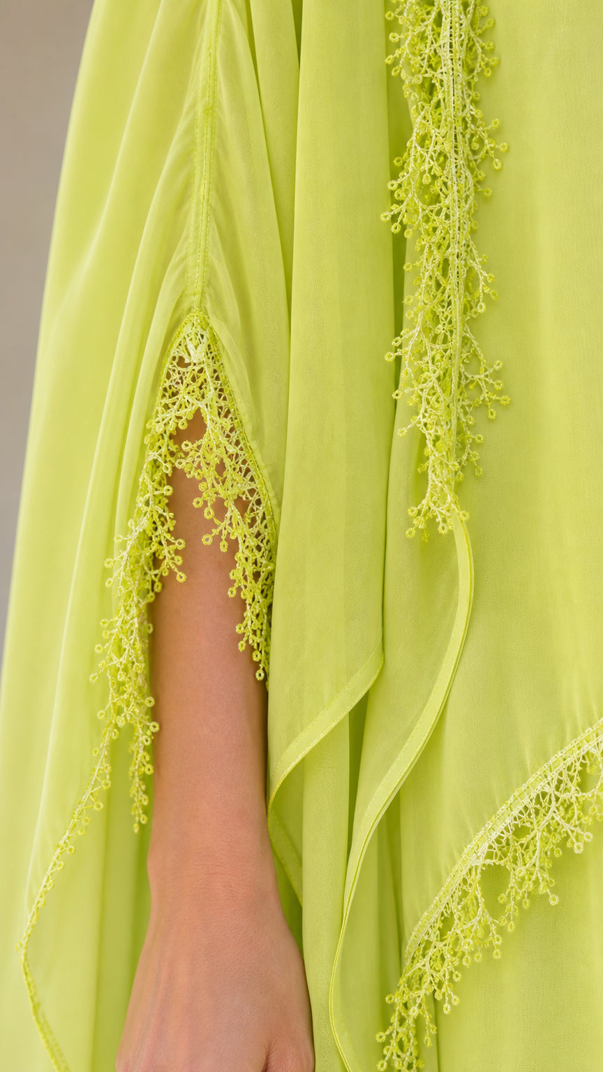 Close-up detail of lace trim on lime green chiffon cape