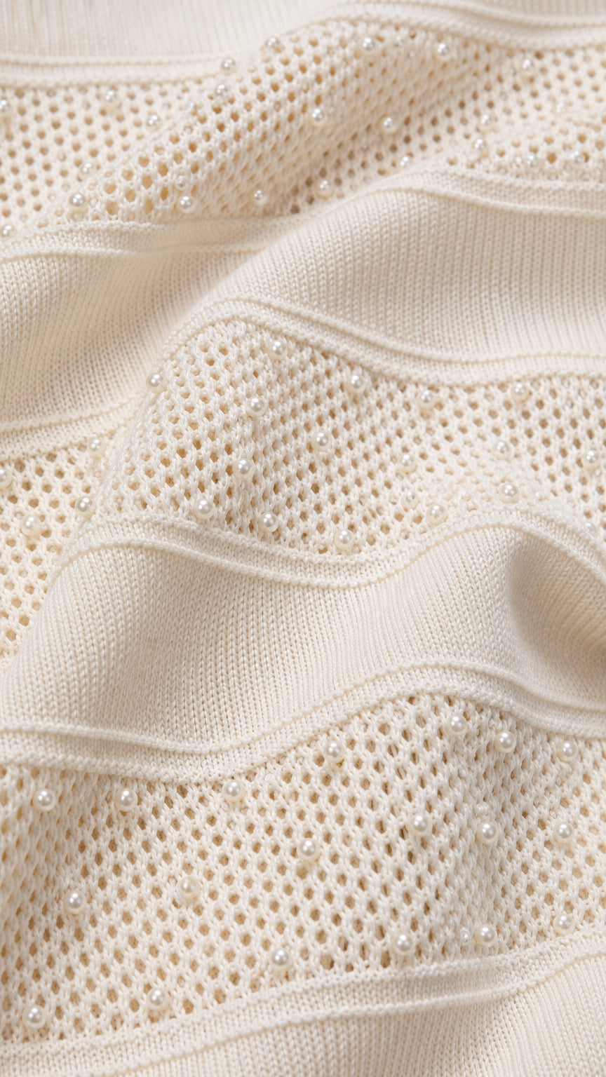 Close-up detail of textured pointelle knit fabric and delicate pearl embellishments