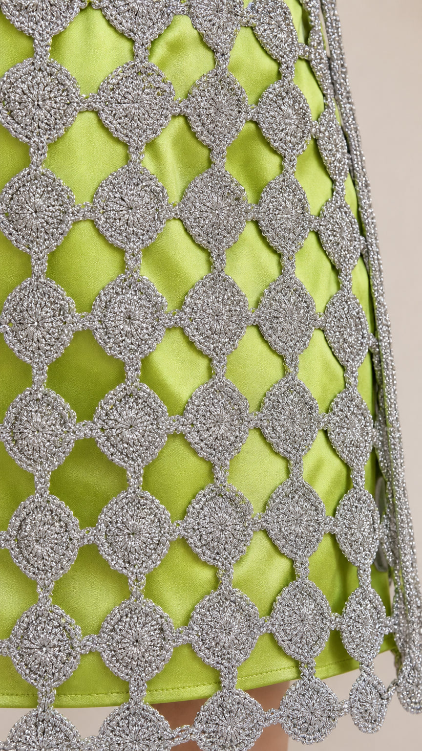 Close-up detail of metallic silver crochet overlay on lime green fabric