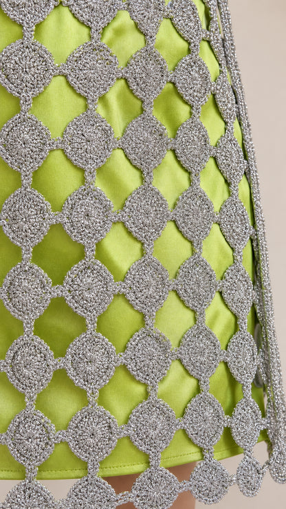 Close-up detail of metallic silver crochet overlay on lime green fabric