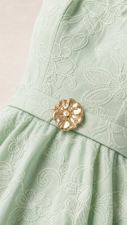Close-up of mint green floral embroidery and gold flower belt buckle