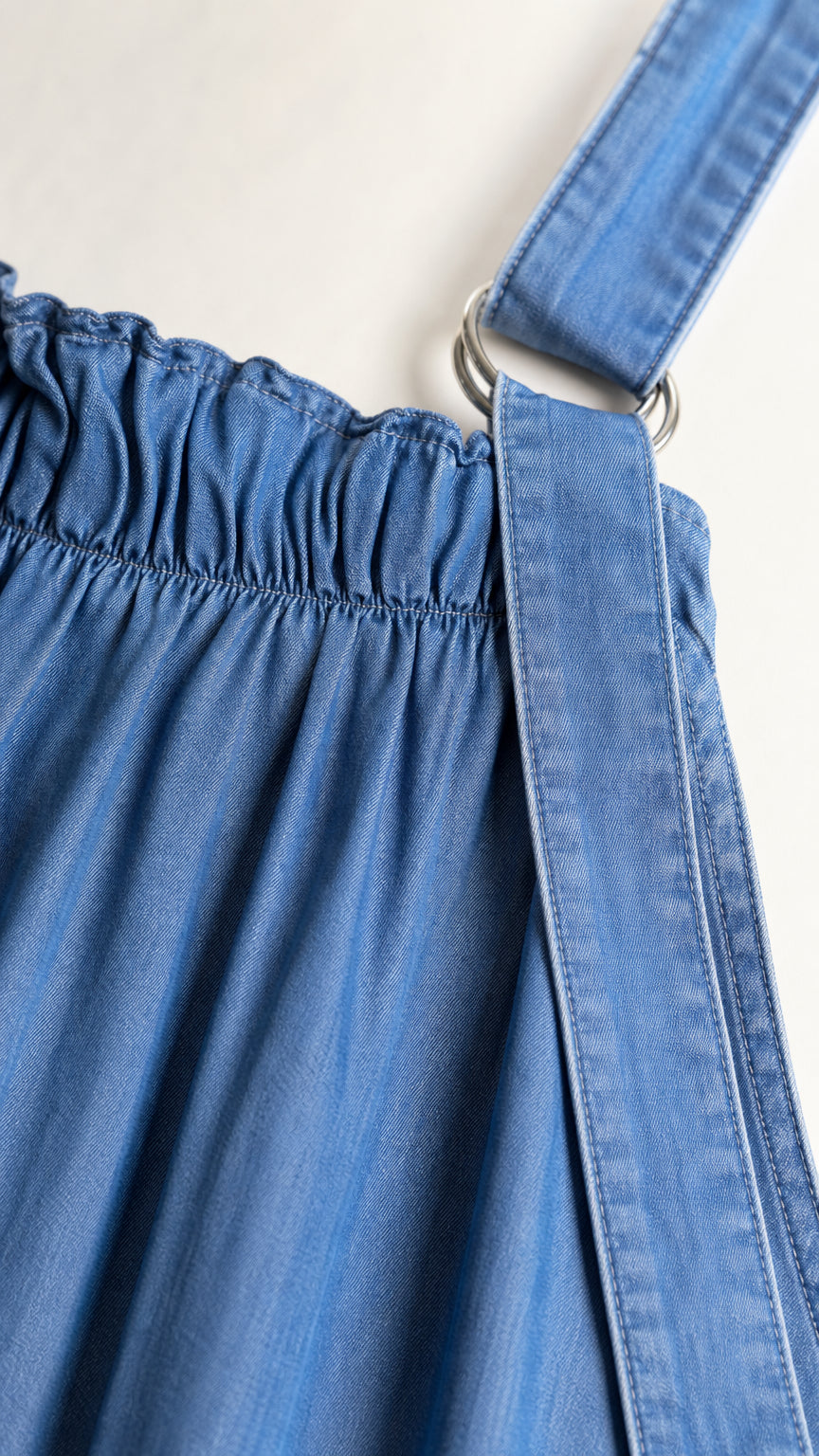 Close up of gathered neckline and strap hardware on blue denim dress