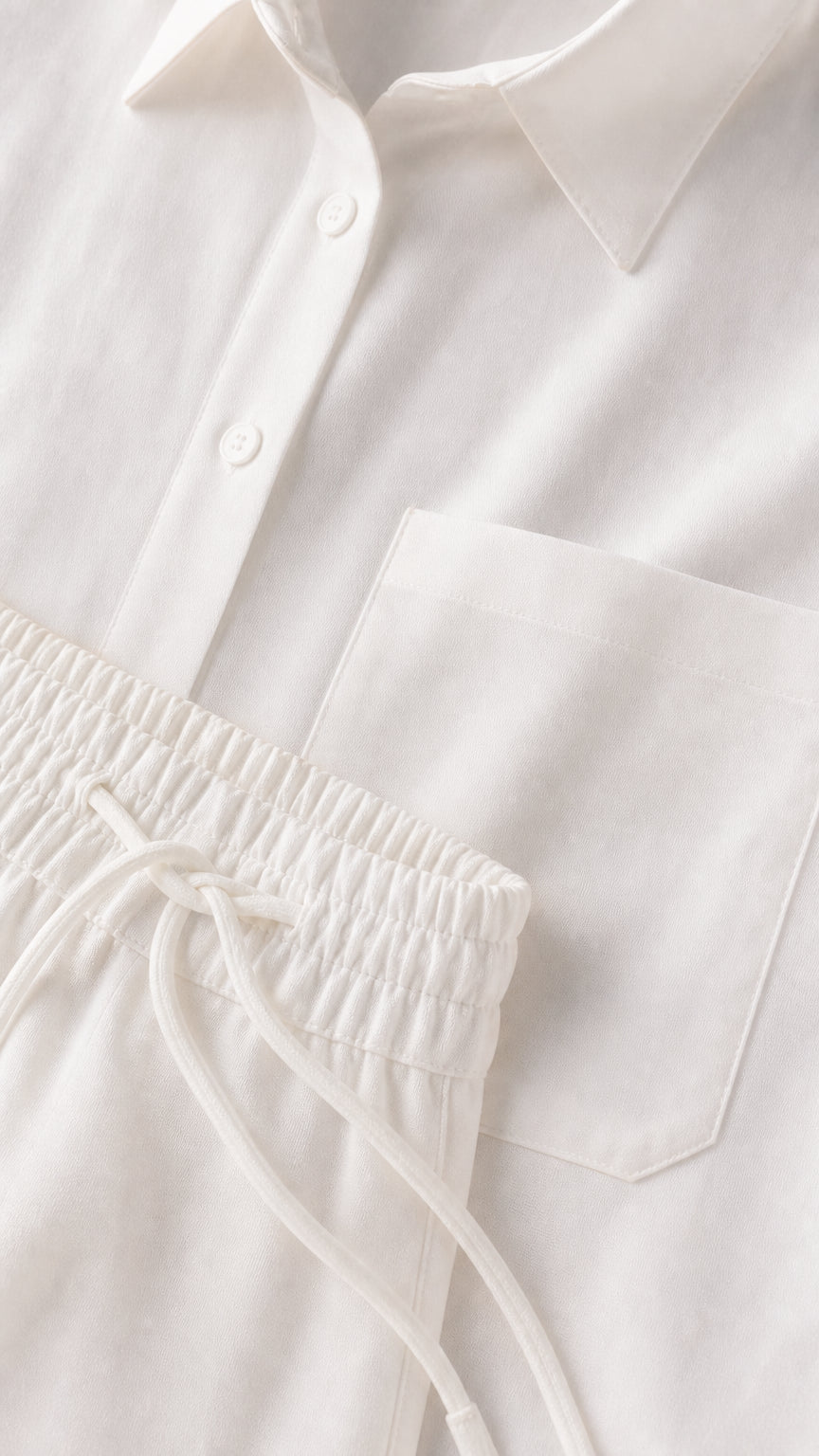 Close-up detail of white button-down shirt collar, pocket, and drawstring pants