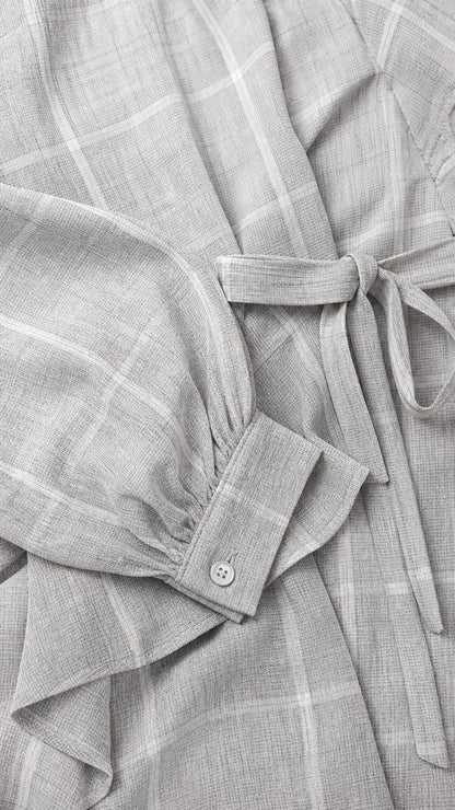 Close-up detail of sleeve cuff, buttons, and tie belt on light grey jumpsuit
