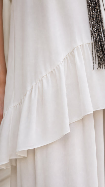 Close-up detail of the asymmetric ruffle hem on the white top