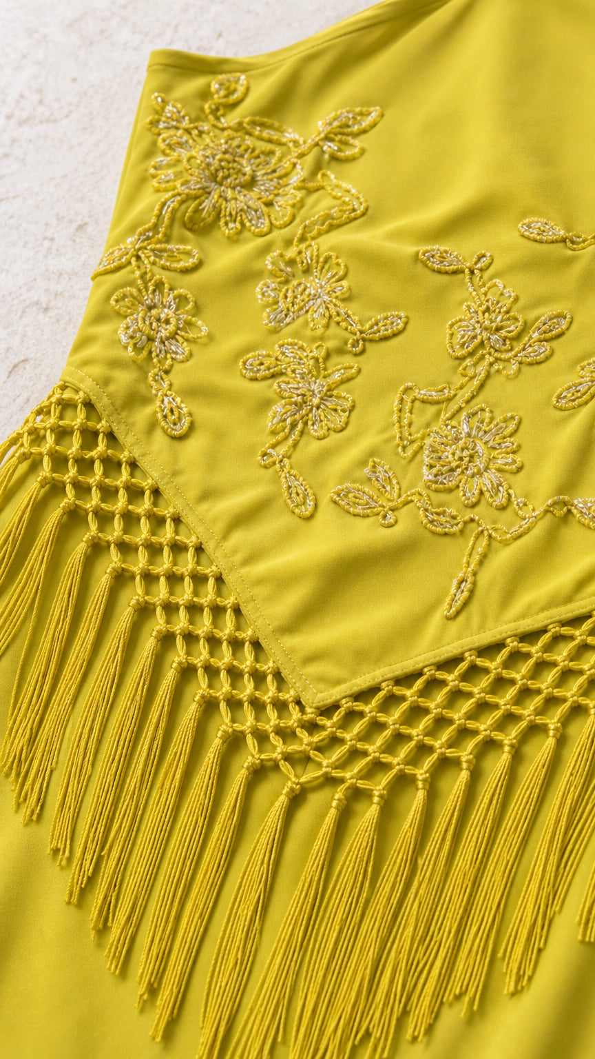 Close-up of floral embroidery and fringe waist overlay on Yellow dress