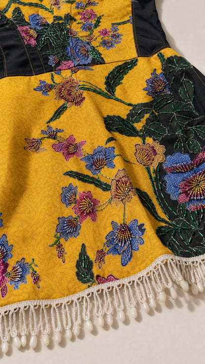 Close-up of embroidery and beaded fringe hem on yellow dress