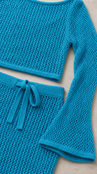 Close-up of blue crochet knit texture, sleeve, and drawstring waistband