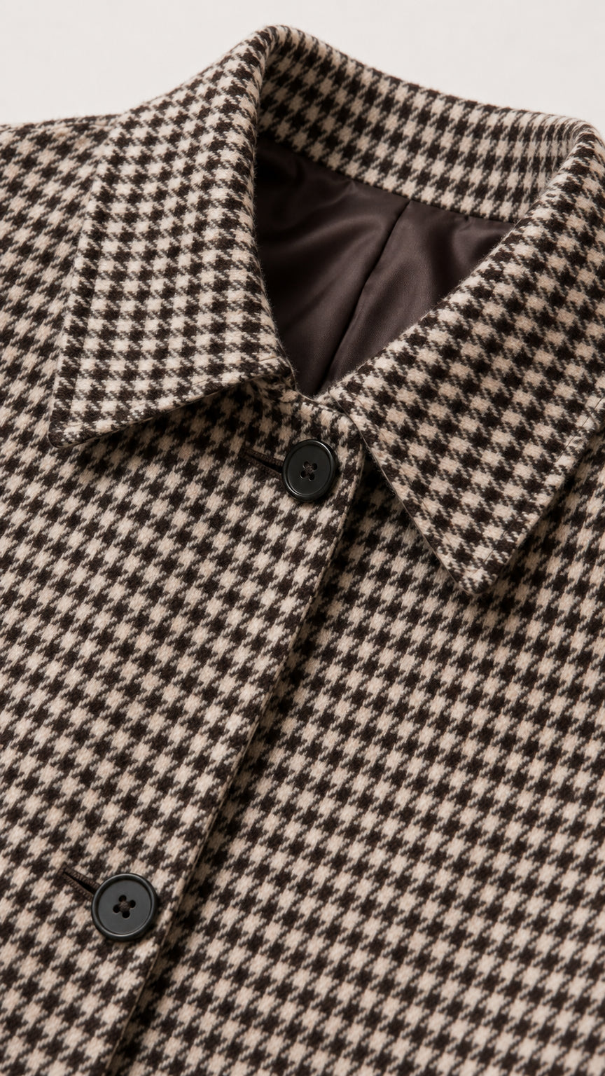 Close-up detail of brown houndstooth woven fabric, collar, and inner lining