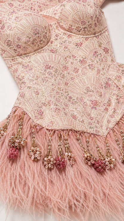 Close-up of beadwork, embroidery, and feather hem on pink dress