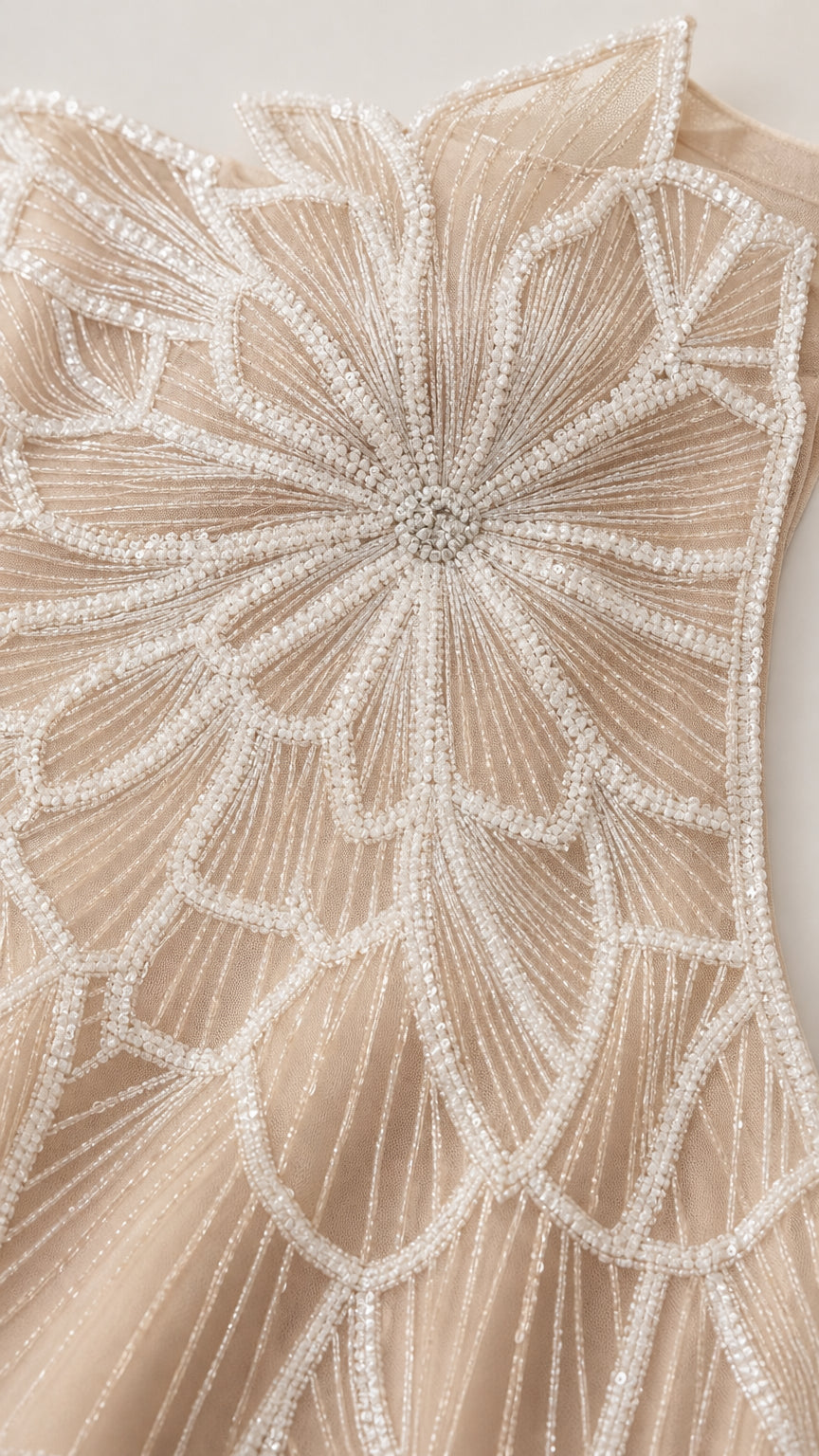 Close-up detail of champagne beaded leaf and floral embroidery on tulle fabric