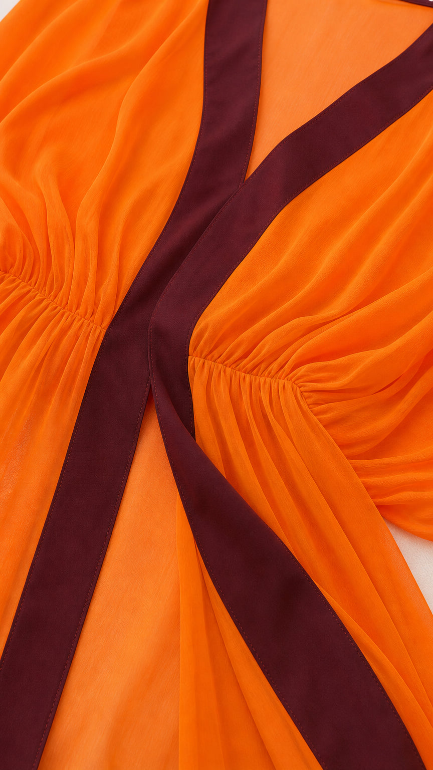 Close-up detail of V-neckline and gathered elastic waist on orange kaftan